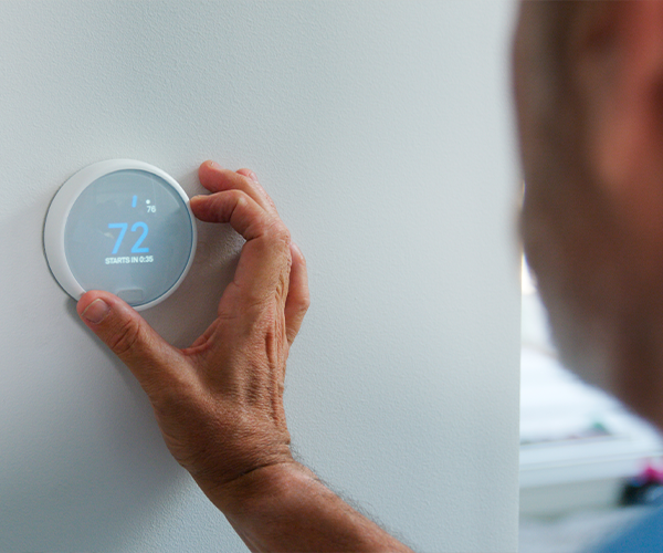 Woman adjusting her smart thermostat to save energy